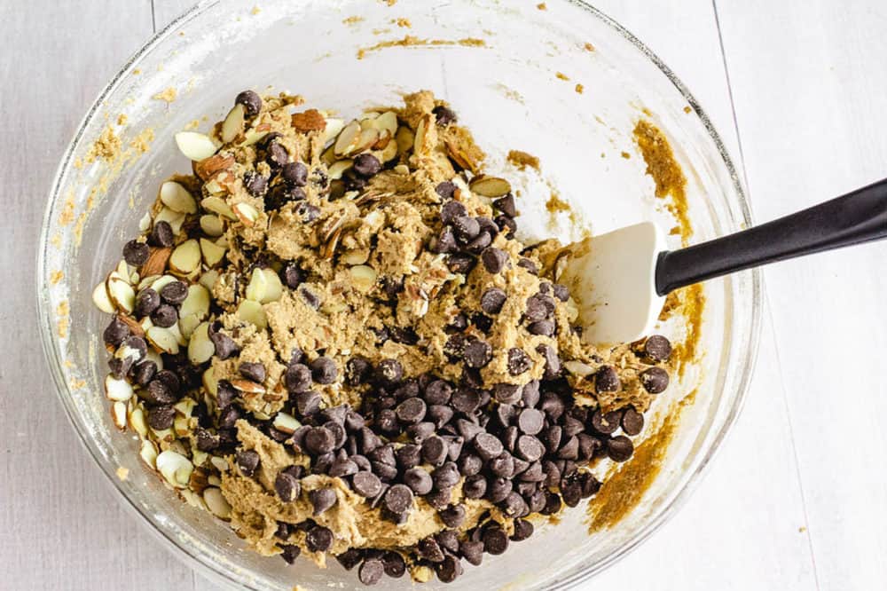 chocolate chips added to cookie dough in a mixing bowl