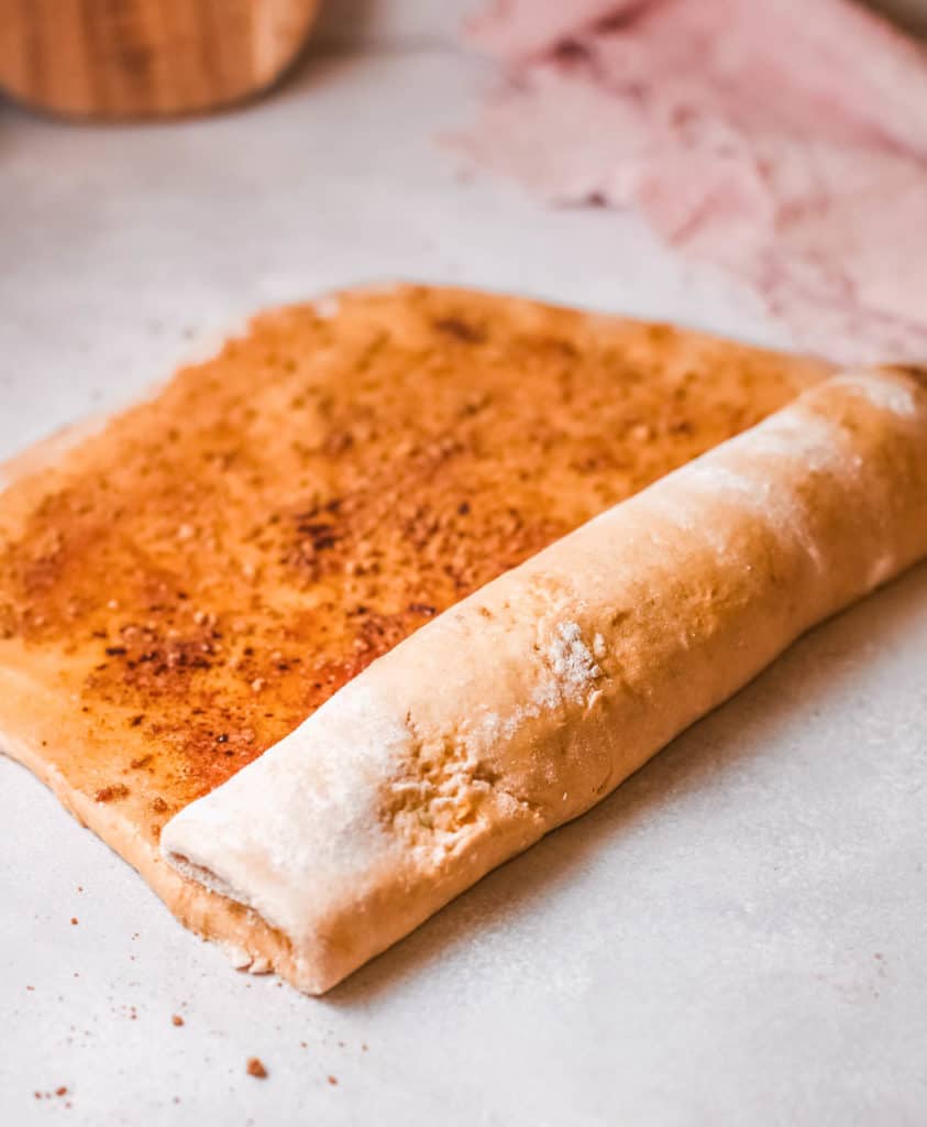 dough rolled into a jelly roll on a cutting board