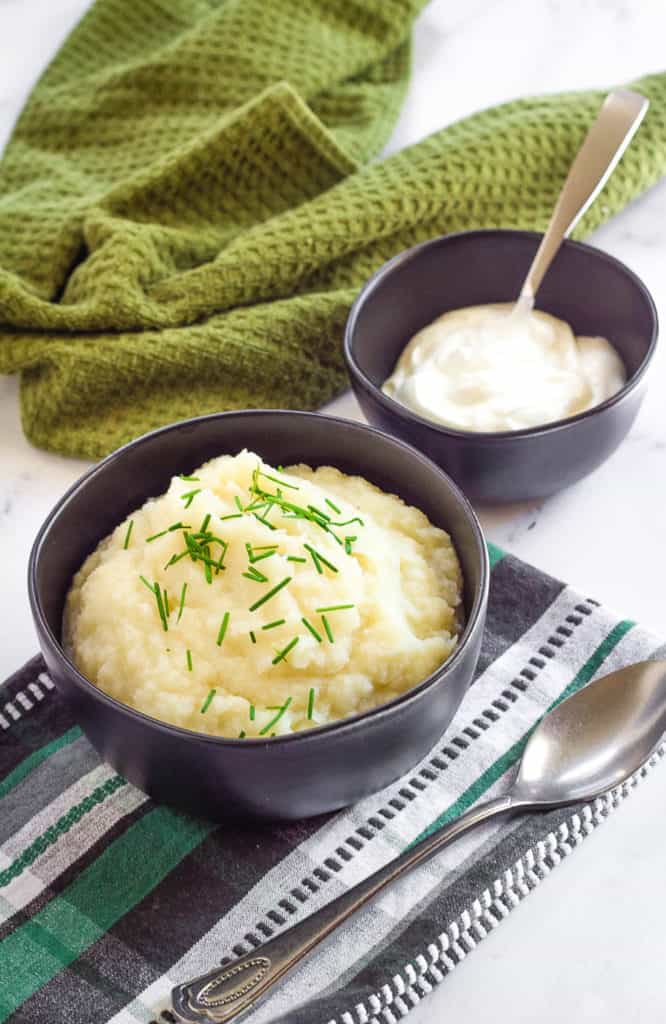 healthy mashed potatoes in a blue bowl against a blue and green cloth