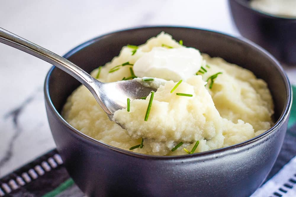 healthy mashed potatoes in a blue bowl against a blue and green cloth