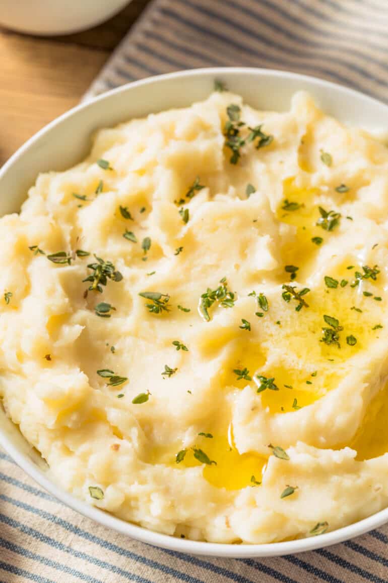Healthy mashed potatoes in a white bowl against a blue and white cloth.