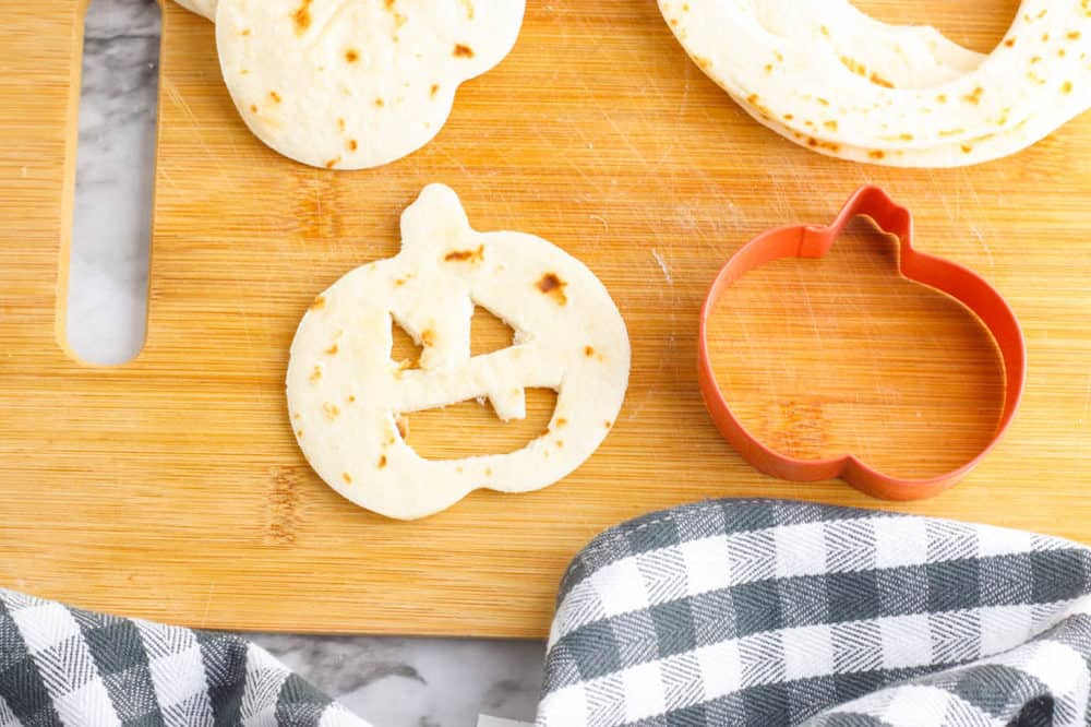 jack o lantern faces cut out of a tortilla on a cutting board