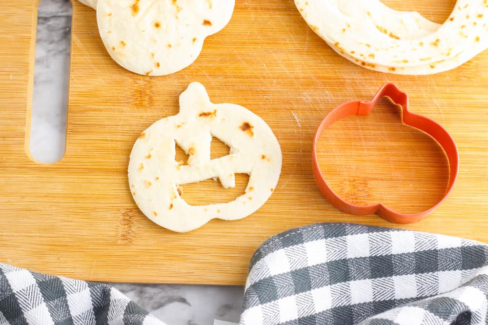 jack o lantern faces cut out of a tortilla on a cutting board