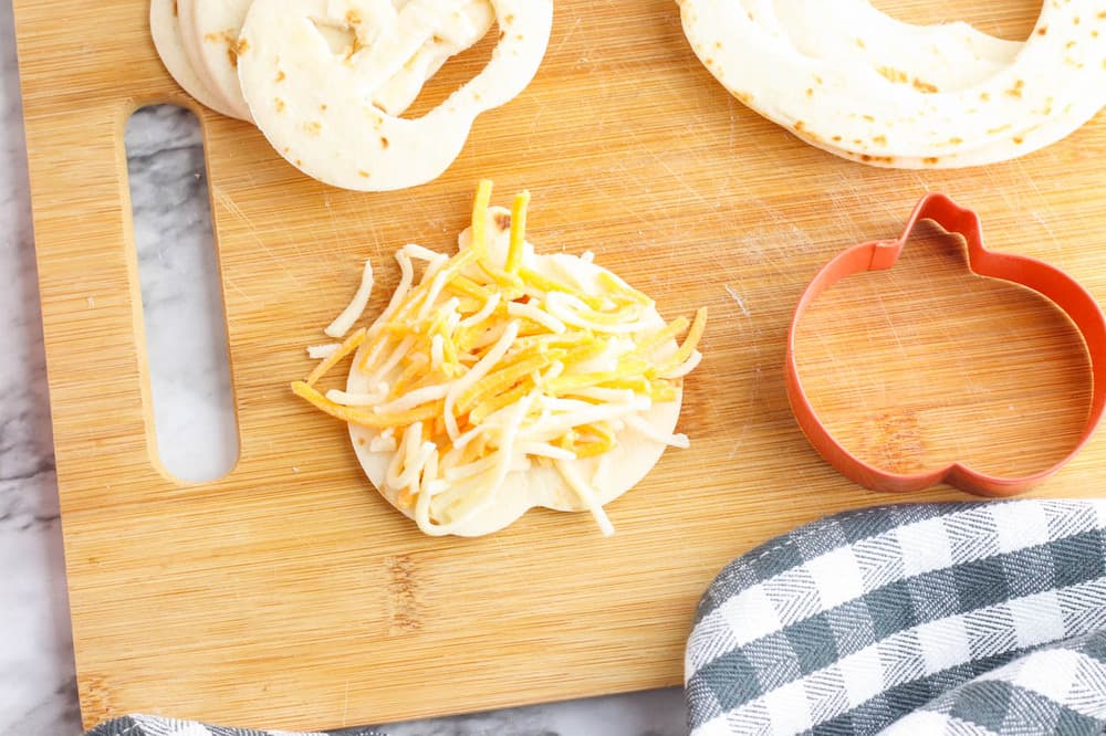cheese added to quesadilla on cutting board