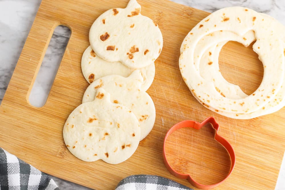 pumpkin shapes cut out of tortillas on a cutting board