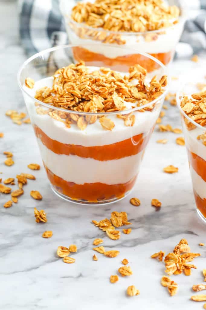 pumpkin yogurt parfaits, with layers of pumpkin puree and yogurt, topped with granola in a glass cup