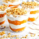 pumpkin yogurt parfaits, with layers of pumpkin puree and yogurt, topped with granola in a glass cup