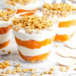 pumpkin yogurt parfaits, with layers of pumpkin puree and yogurt, topped with granola in a gl، cup