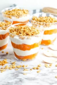 pumpkin yogurt parfaits, with layers of pumpkin puree and yogurt, topped with granola in a glass cup