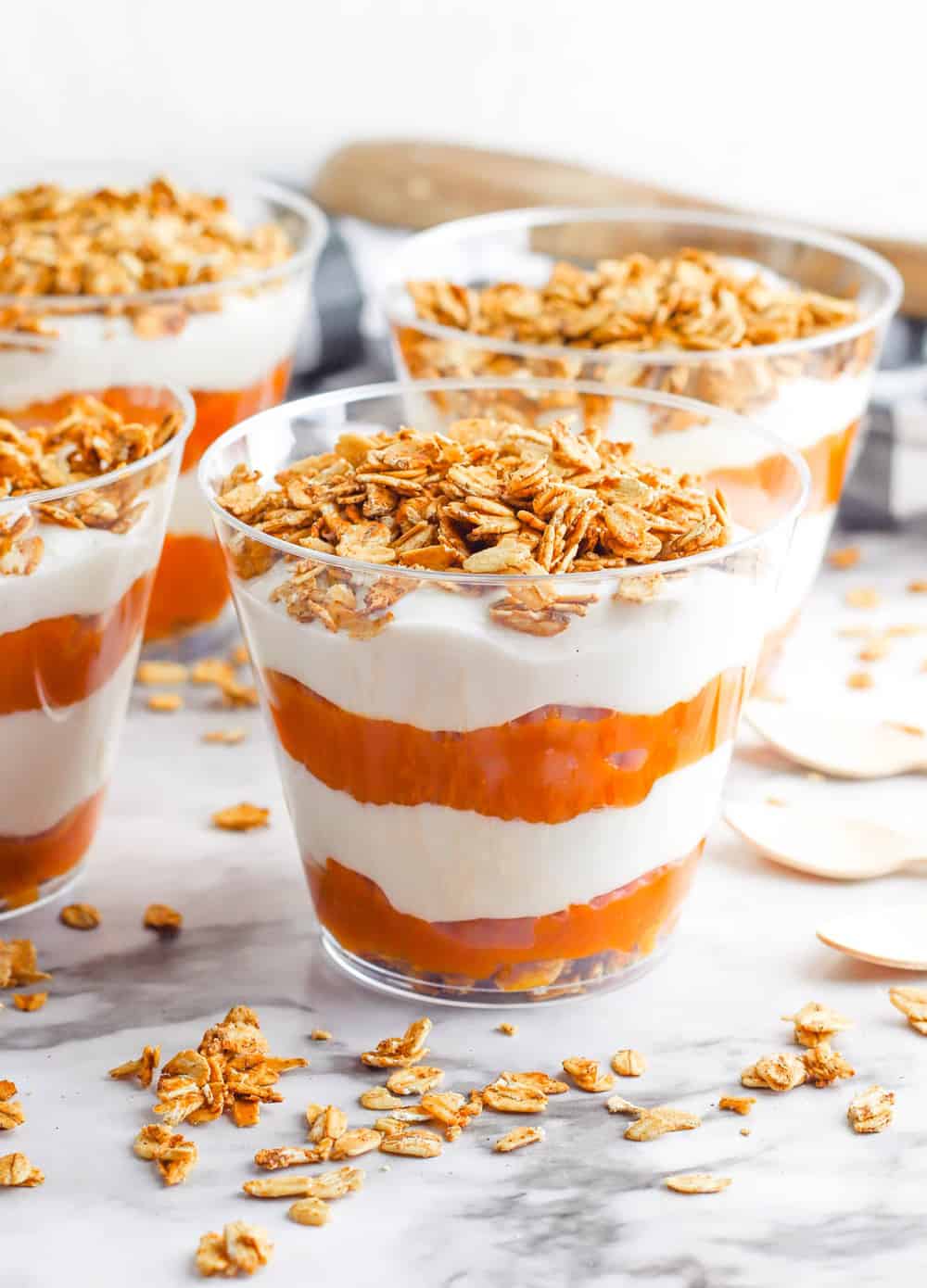 pumpkin greek yogurt parfait, with layers of pumpkin puree and yogurt, topped with granola in a glass cup