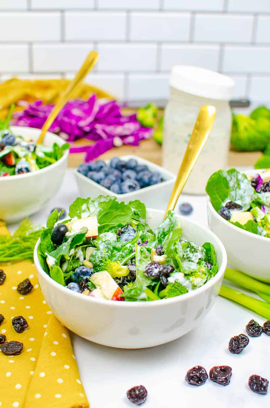 superfood salad served in a white bowl with broccoli, blueberries, sweet Fuji apples, cabbage, spinach, dried cherries, pine nuts, and a healthy ranch dressing