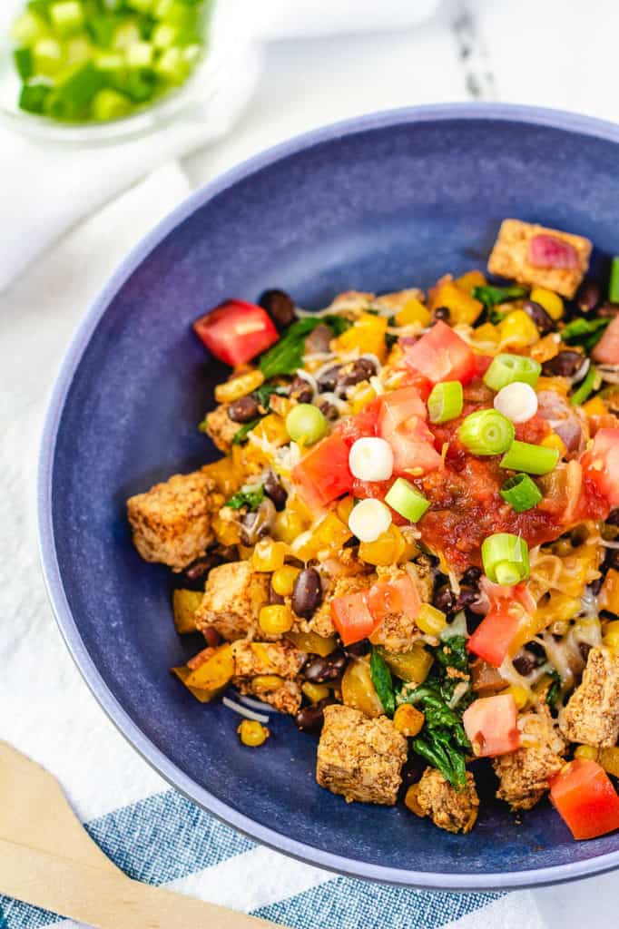 tofu scramble topped with tomatoes, salsa, green onions in a blue bowl