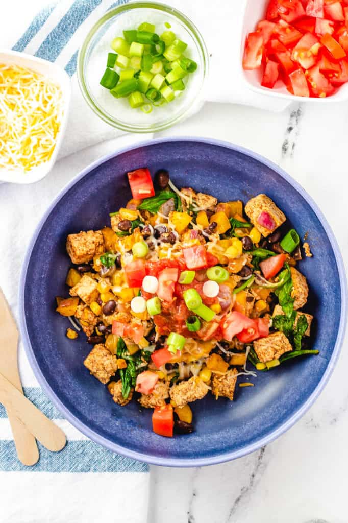 tofu scramble recipe topped with tomatoes, salsa, green onions in a blue bowl