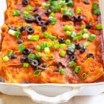 vegan enchiladas, fresh out of the oven, served in a casserole dish and topped with green onions and olives
