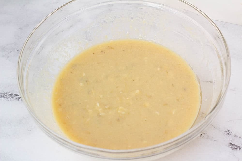Mashed bananas and other wet ingredients combined in a bowl.