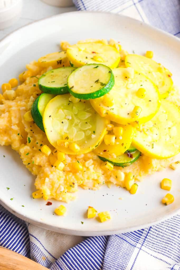 gluten free cheesy polenta topped with zucchini, corn and herbs, served on a white plate - 30 minute vegetarian meals