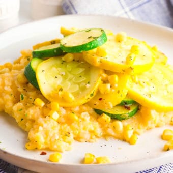 gluten free cheesy polenta topped with zucchini, corn and herbs, served on a white plate