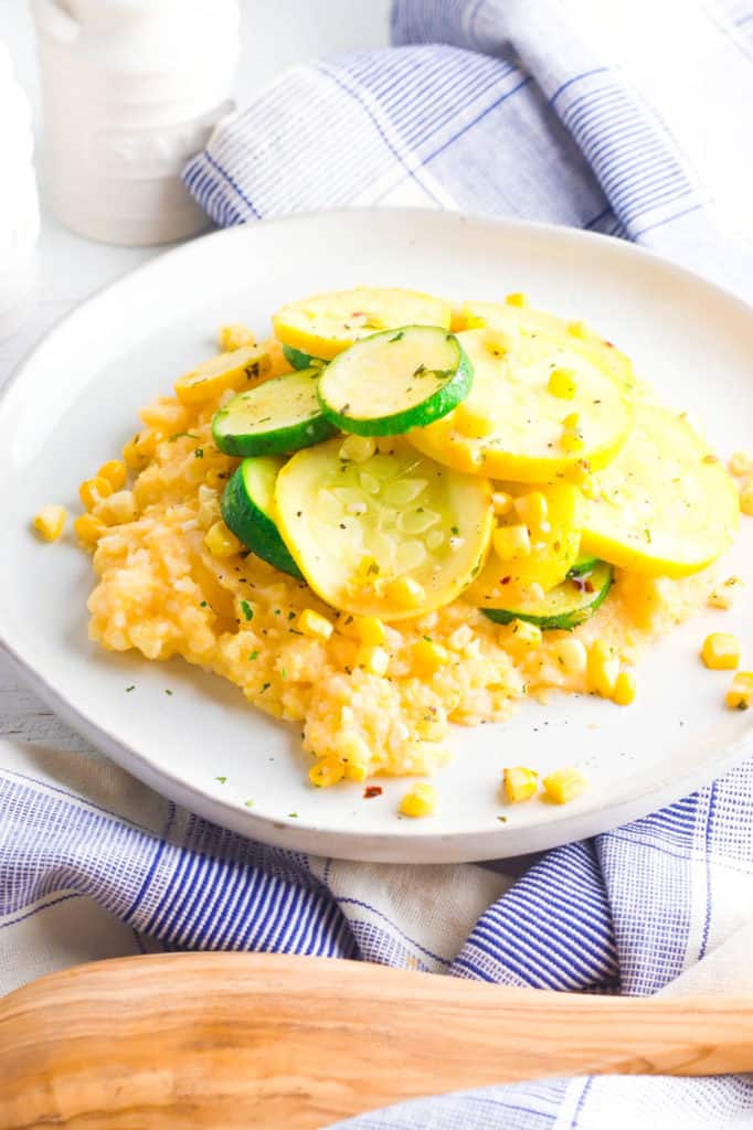 gluten free cheesy polenta topped with zucchini, corn and herbs, served on a white plate - vegetarian gluten free recipes