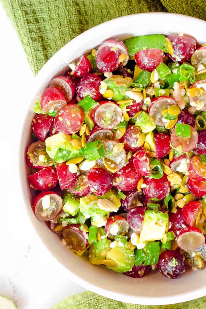 recipe for grape salad with avocado and cojita cheese in a white bowl