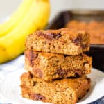 healthy chocolate chip banana bread slices stacked on top of each other on a white plate