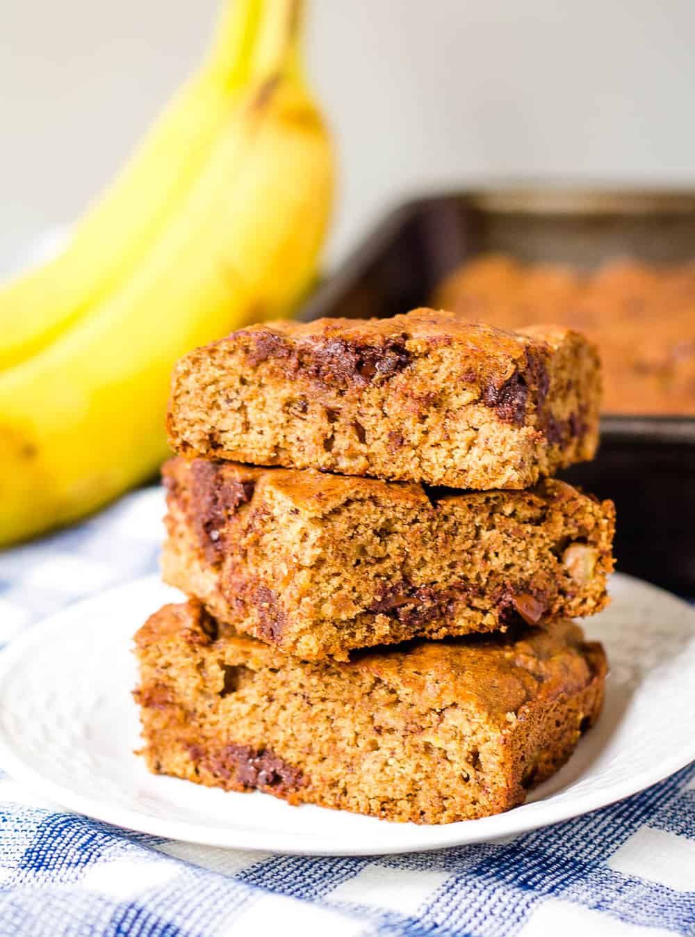 healthy chocolate chip banana bread slices stacked on top of each other on a white plate