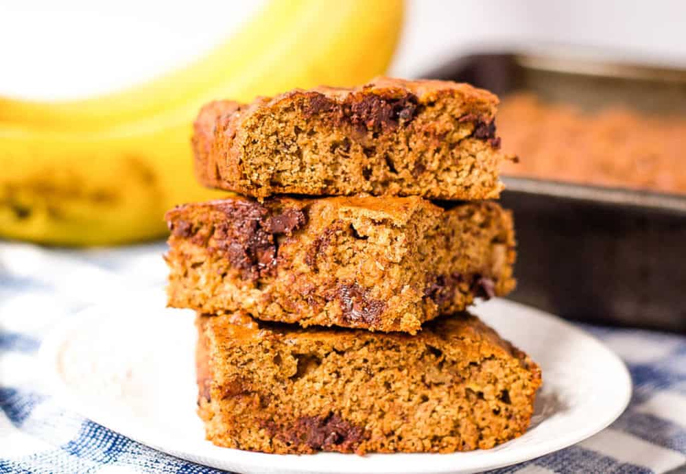 healthy chocolate chip banana bread slices stacked on top of each other on a white plate