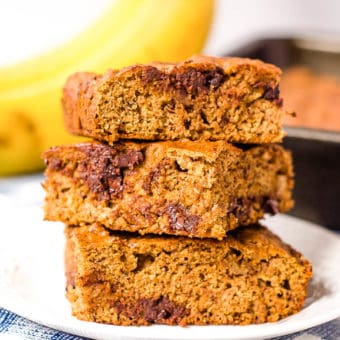 healthy chocolate chip banana bread slices stacked on top of each other on a white plate