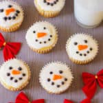 snowman cupcakes against a grey background with a glass of milk
