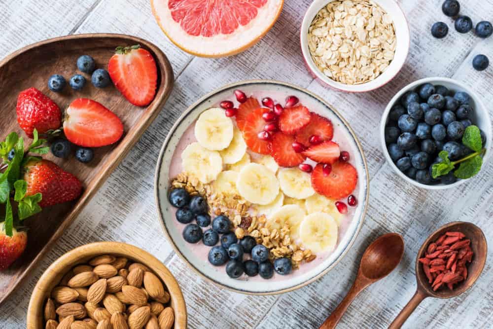 healthy snacks for toddlers - toddler snacks - smoothie bowl with banana slices, strawberry, blueberries, granola and pomegranate seeds. 