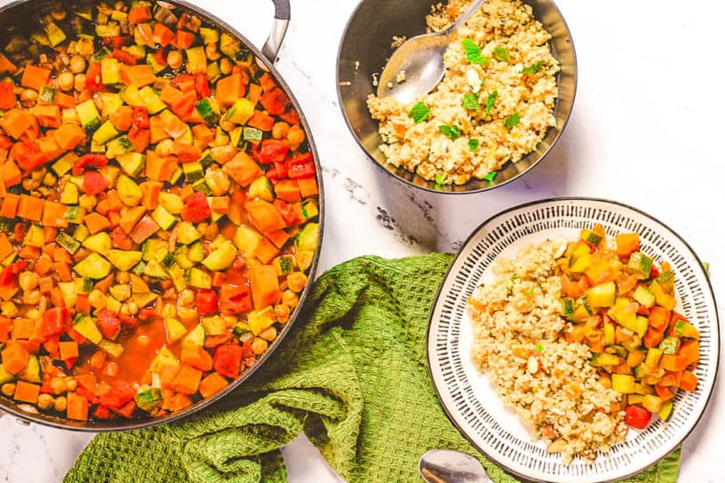 moroccan stew with chickpeas and quinoa couscous served on a white plate with pot of stew in the background