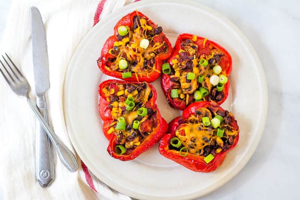 chili stuffed peppers with black beans and mushrooms, served on a white plate