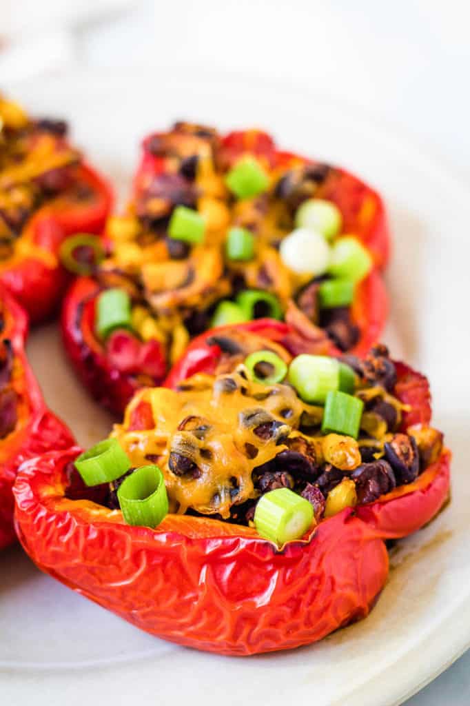 chili stuffed peppers with black beans and mushrooms, served on a white plate