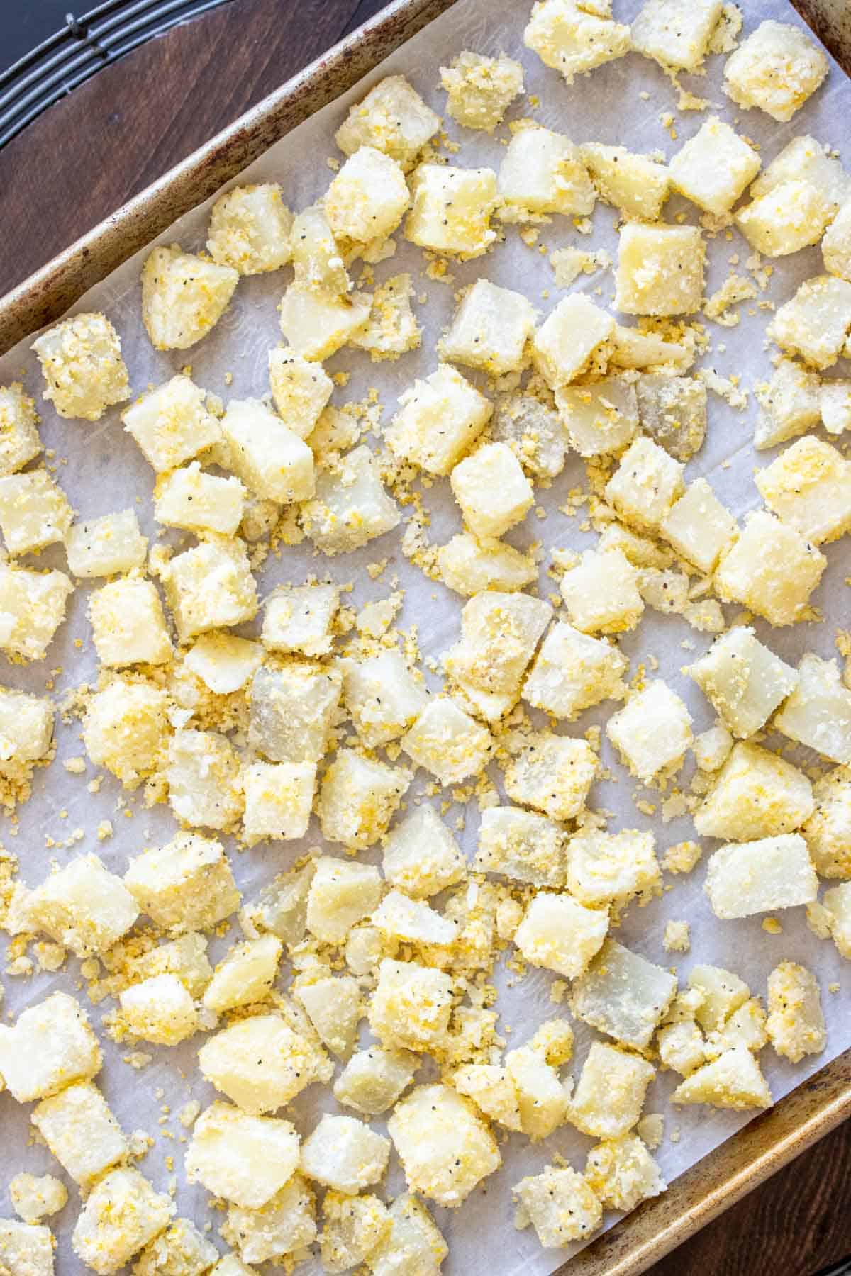 coated potatoes spread out on baking tray with parchment paper