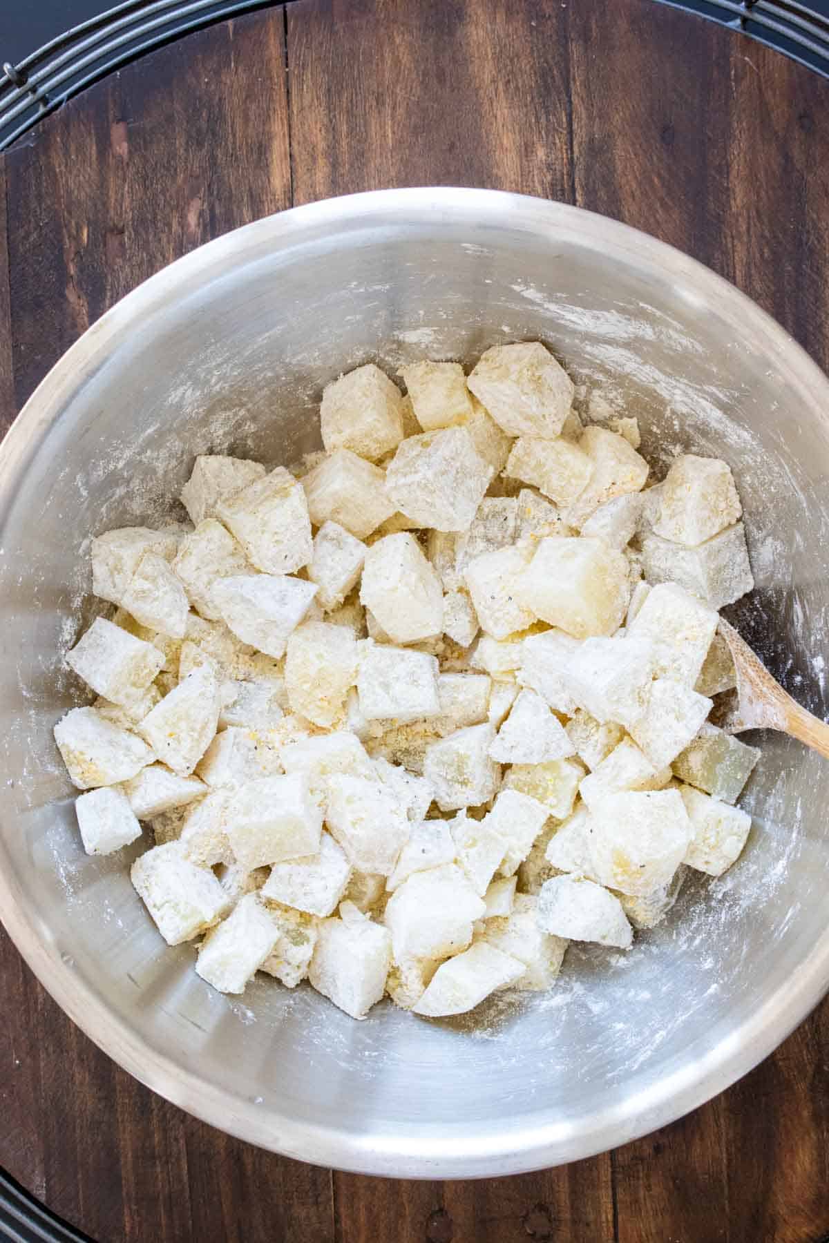 a bowl with cubed potatoes coated in cornstarch and cornmeal