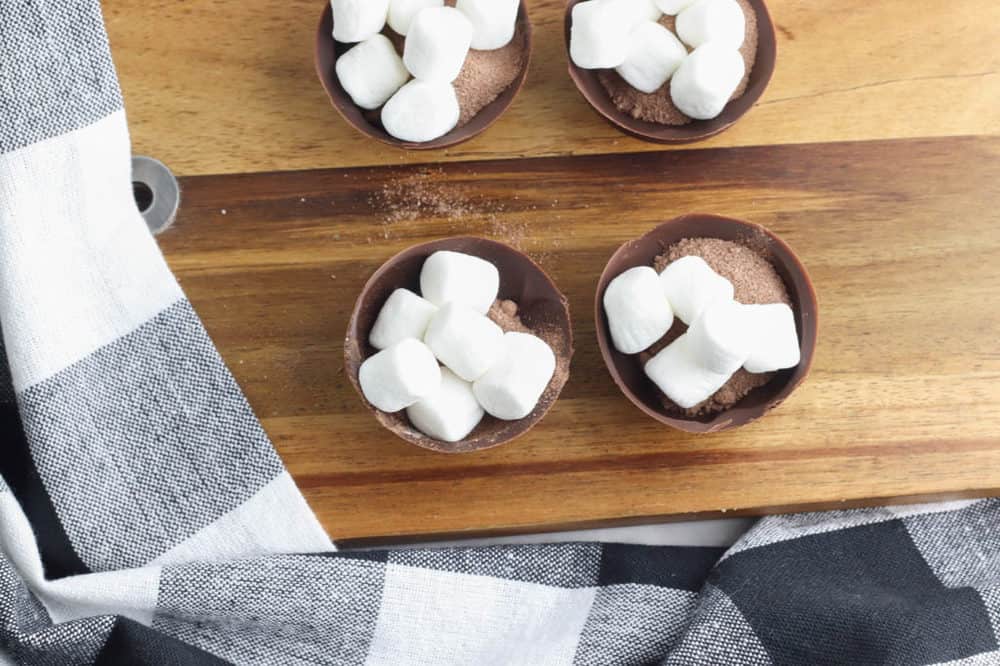 marshmallows and cocoa powder in half shell of chocolate