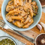 vegan mushroom stroganoff served in a blue bowl with garnishes on the side, top view