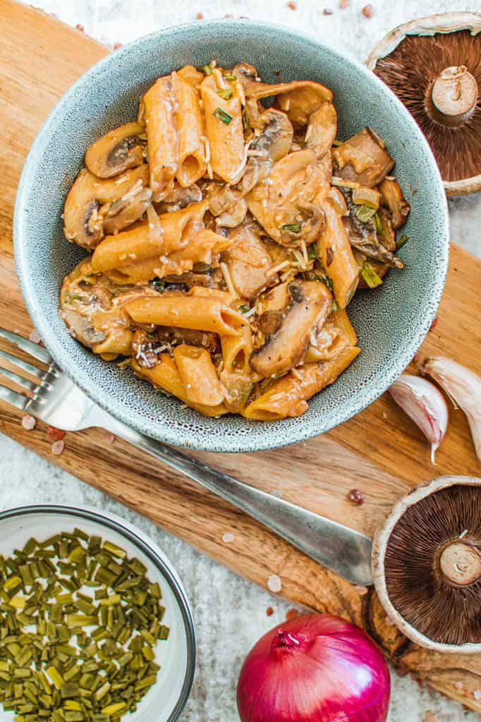 vegan mushroom stroganoff served in a blue bowl with garnishes on the side, top view