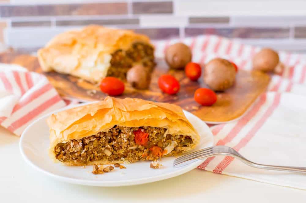 vegan wellington with lentils and mushrooms, served on a wooden cutting board