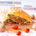 vegan wellington with lentils and mushrooms, served on a wooden cutting board