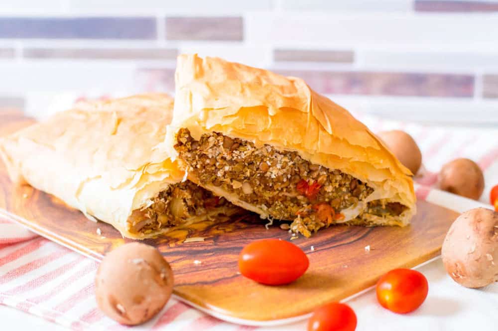 vegan wellington with lentils and mushrooms, served on a wooden cutting board