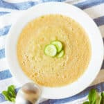 cucumber gazpacho served in a white bowl, garnished with cucumber slices