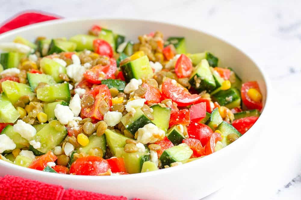 feta salad with lentils, cucumbers, tomatoes, corn in a bowl - healthy side dishes