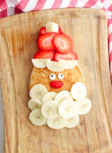 santa pancakes - christmas and holiday breakfast - made with bananas for a beard, strawberries for a hat, and candy eyes on top of a homemade pancake
