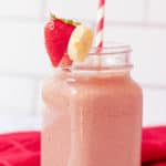 strawberry and banana smoothie in a glass mason jar with a straw