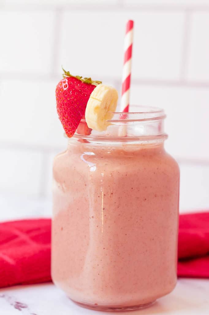 strawberry and banana smoothie in a glass mason jar with a straw