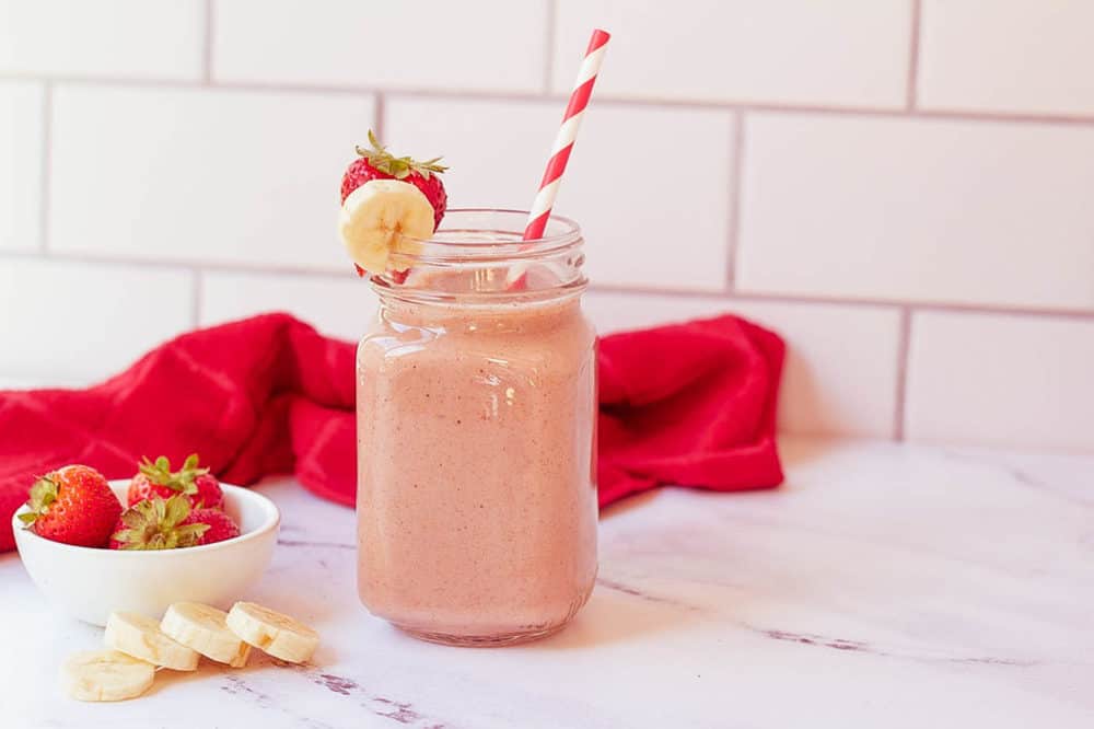 strawberry and banana smoothie in a glass mason jar with a straw