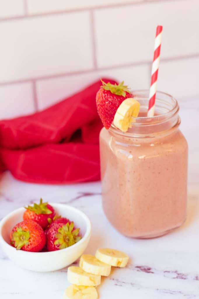 strawberry and banana smoothie in a glass mason jar with a straw