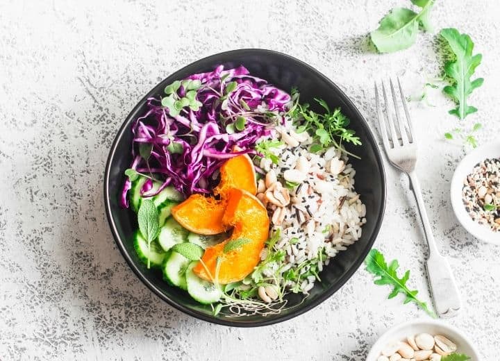 vegetarian gluten free recipe with rice, squash, purple cabbage, and cucumber in black bowl