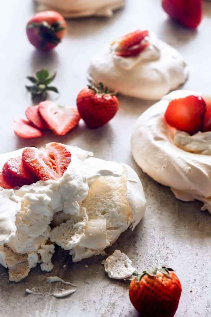 mini pavlovas topped with whipped cream and strawberries