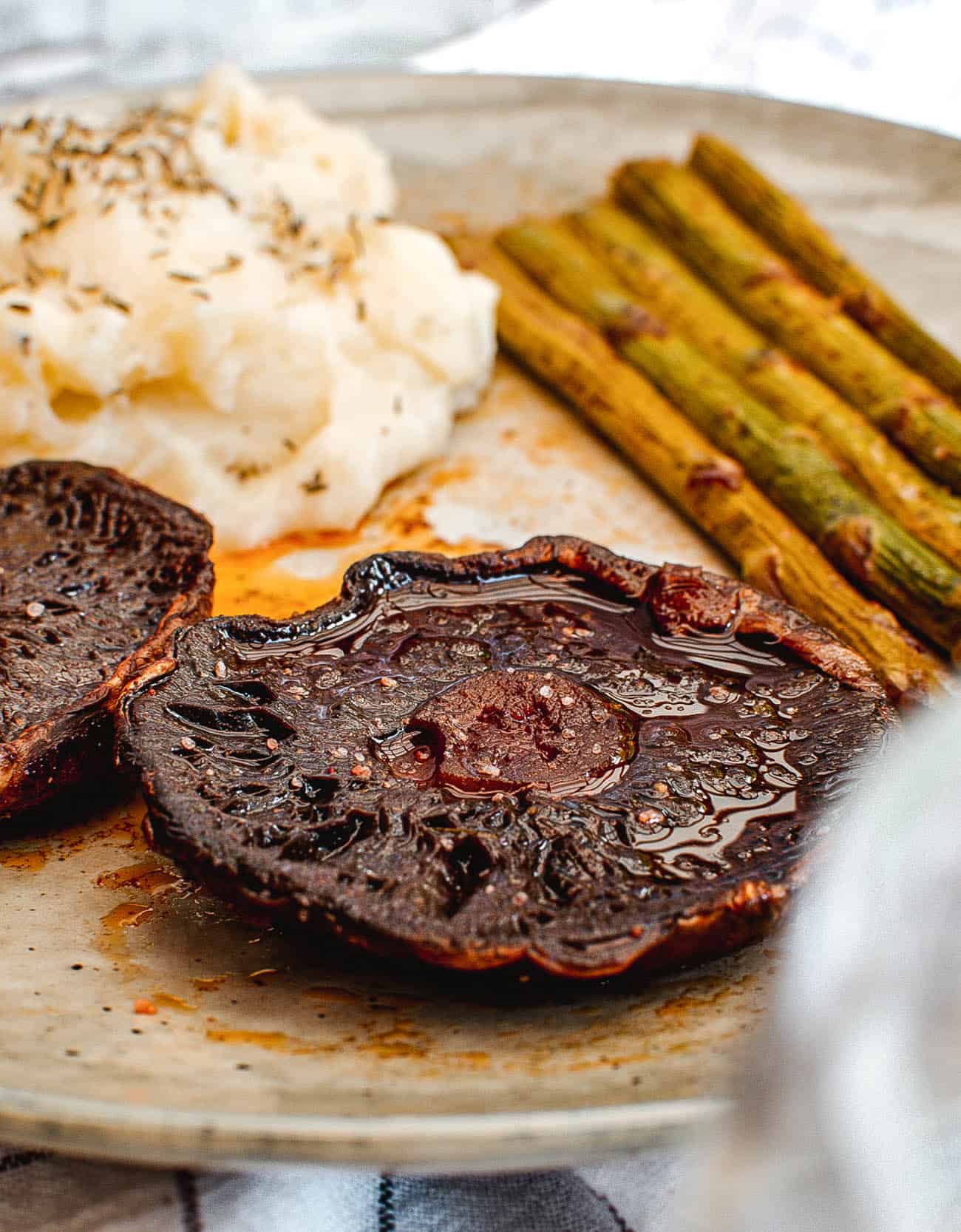 portobello mushroom steaks paired with mashed potatoes and asparagus served on a white plate